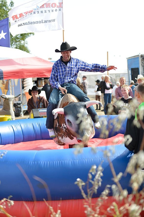 A man balancing on a mechanical bull in a ring, highlighting a fun mechanical bull rental option for parties and gatherings.